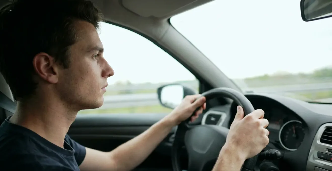 Jeune conducteur au volant concentré sur la route, assurance auto deuxième conducteur